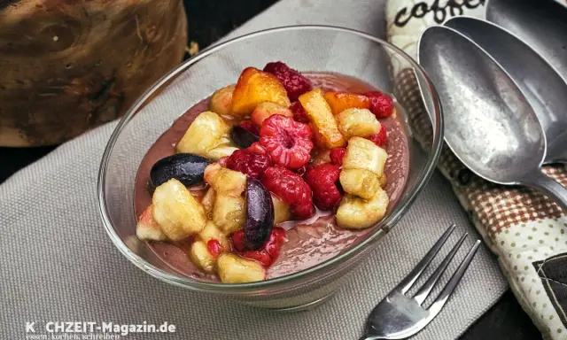 Schokoladige smoothie bowl mit frischen Himbeeren, Bananenstücken und Blaubeeren. Ein gesunder Genuss!