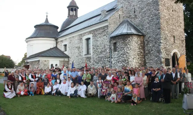 Wielka grupa ludzi, w tym dzieci i duchowni, pozuje przed zabytkowym kościołem parafii Skarżysko.