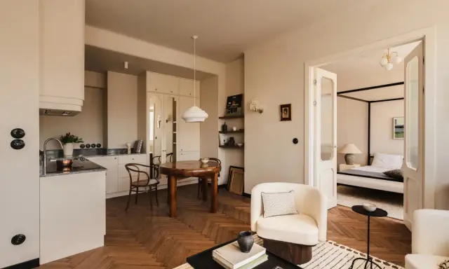 Jak urządzić salon? Jasne, przytulne wnętrze z aneksem kuchennym, jadalnią i sypialnią. Drewniana podłoga w jodełkę, wygodne fotele i stylowe dodatki.