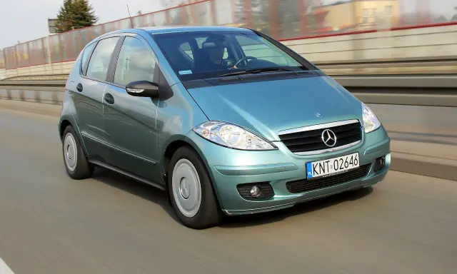 Turkusowy Mercedes A170 na drodze, z widocznym kierowcą.