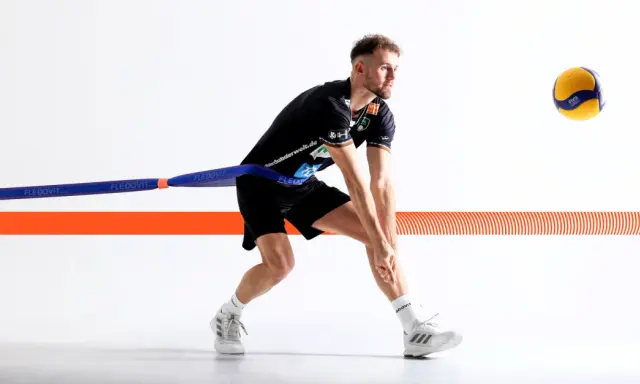 Volleyballspieler im Krafttraining mit Widerstandsband, bereit für den Aufschlag.