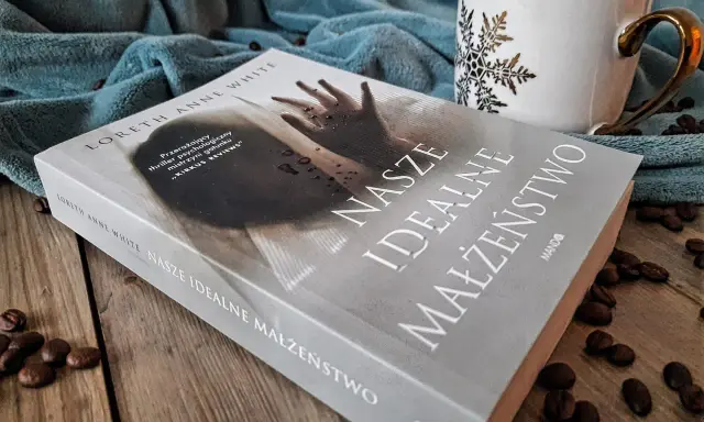 Książka "Nasze idealne małżeństwo" na drewnianym blacie, obok filiżanki i ziaren kawy.
