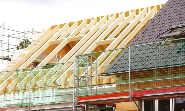 Neuer Dachstuhl im Bau, Gerüst und Schutznetze. Informieren Sie sich über die dachstuhl erneuern kosten.