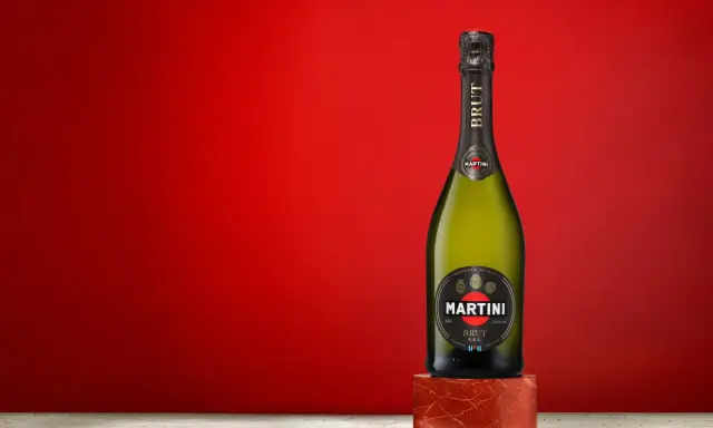 Butelka Martini Brut 7.5% alc. vol. na tle czerwonej ściany.