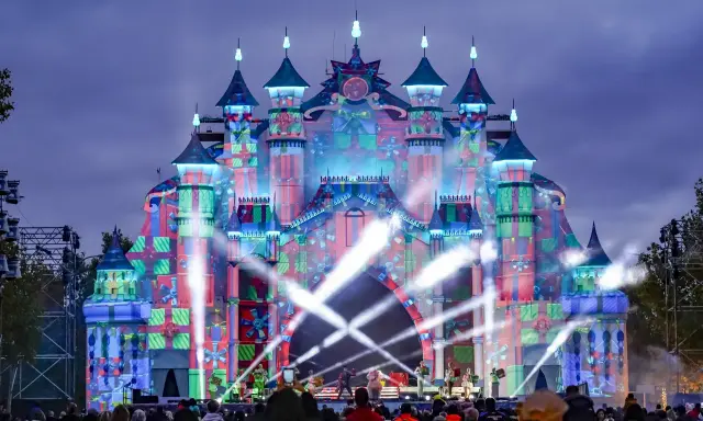 Castillo de luces y regalos en el parque navidad Torrejón. Artistas actúan en un escenario frente a la multitud.