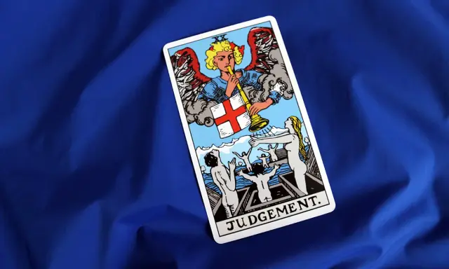 Karta Sąd Ostateczny Tarot. Anioł gra na trąbie, budząc ludzi z grobów.