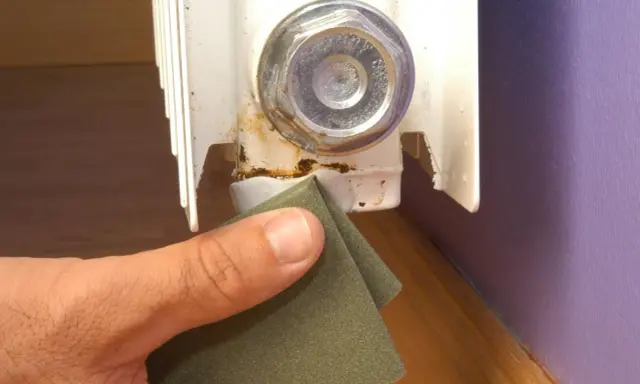 Lijando la zona oxidada de un radiador para prevenir una fuga.