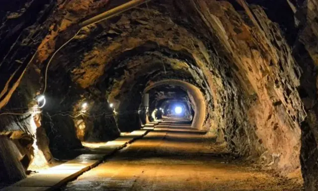 Wąski tunel w kopalni, oświetlony lampami, prowadzi w głąb ziemi. To jedne z wielu tajemniczych jaskiń Dolnego Śląska.
