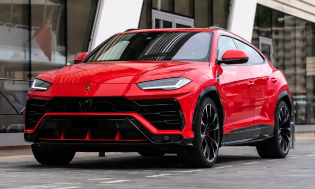 Un imponente Lamborghini Urus rojo, listo para la acción, con su diseño agresivo y llantas negras.