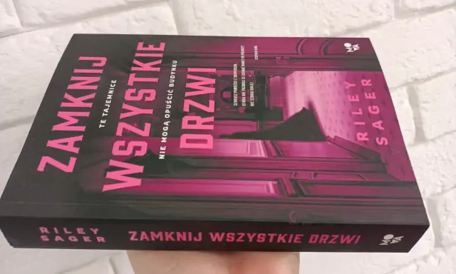 Okładka książki "Zamknij wszystkie drzwi" z różowymi neonowymi literami na czarnym tle.