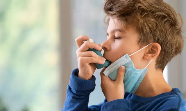 Junge mit Inhalator und Maske. Gute Behandlung beeinflusst die asthma lebenserwartung positiv.
