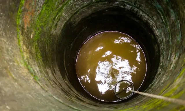 Puits profond avec eau trouble, une corde et un seau pour aider à éliminer le fer dans l'eau de forage.