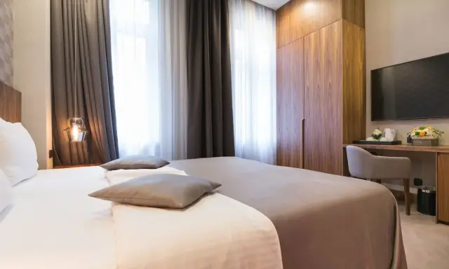 Eleganckie pokoje hotelowe: łóżko, szafa, biurko z TV. Idealne nazwy pokoi hotelowych dla komfortowego pobytu.