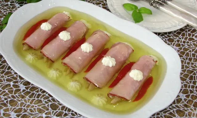 Roladki z szynki z papryką w galarecie, ozdobione kleksami majonezu. Elegancka przystawka na specjalne okazje.