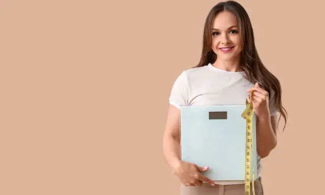 Femme souriante tenant une balance et un mètre ruban, prête à perdre 10 kilos.