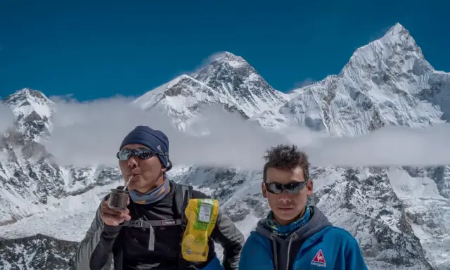 Niesamowity widok z Mount Everest. Dwóch wspinaczy odpoczywa, jeden pije yerba mate, podziwiając majestatyczne szczyty.