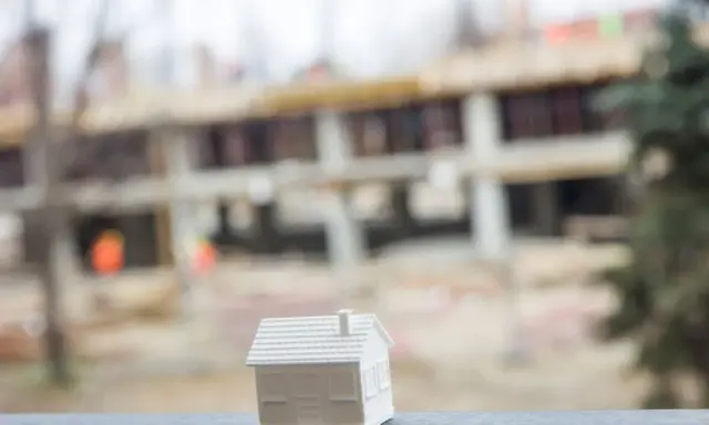 Biały model domu na tle budowy. Czy to przyszłe inwestycje jednostek samorządu terytorialnego?