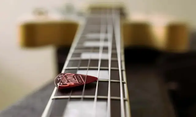 Médiator sur le manche d'une guitare, prêt à jouer une gamme arabe.