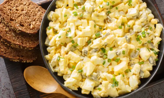 Cremiger Eiersalat mit Gurkenstückchen und Schnittlauch, garniert, serviert mit Vollkornbrot. Ein einfaches eiersalat rezept.