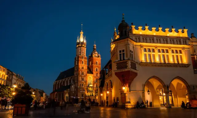 Wieczorny spacer po Rynku Głównym w Krakowie. Sukiennice i Kościół Mariacki oświetlone, tworzą magiczną atmosferę na udany weekend w Krakowie.