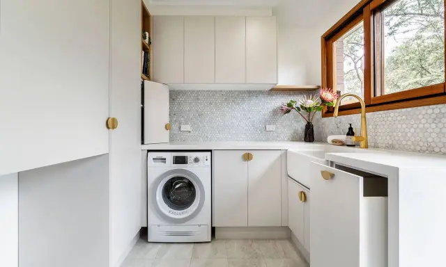 Lavanderia piccola moderna con lavatrice, lavello bianco, rubinetto dorato e finiture eleganti. Ottime idee per sfruttare ogni spazio.