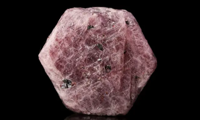 Cristallo grezzo di corindone rosa, con inclusioni scure. Il corindone, con il suo significato di forza e passione, si presenta in questa forma naturale.