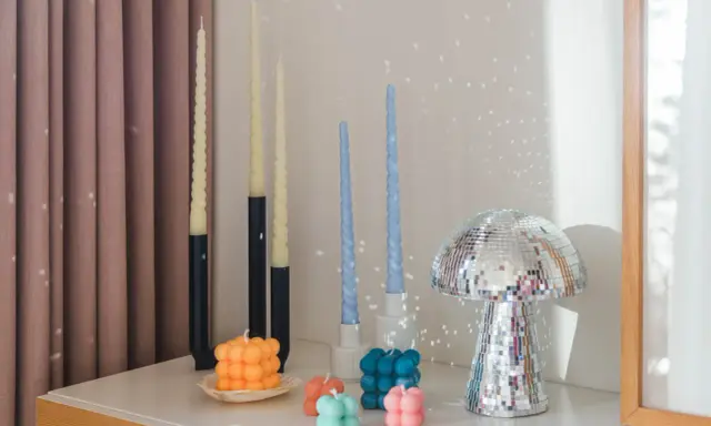 En samling av DIY ljus i olika former och färger, inklusive bubbel- och vridna ljus, samt en glittrig svampformad dekoration.