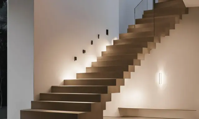 Un élégant miroir reflète la lumière douce d'une montée d'escalier moderne, créant une ambiance chaleureuse et accueillante.