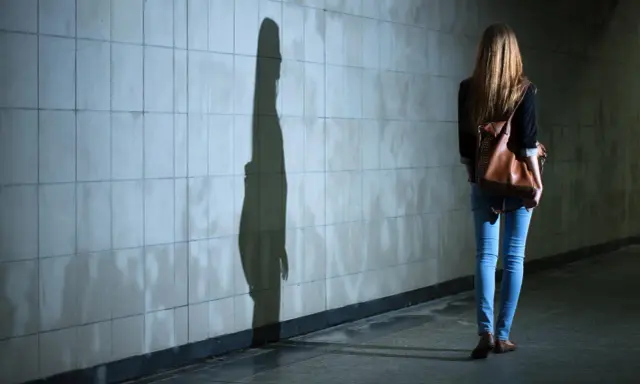 Dziewczyna z plecakiem idzie przez tunel, jej cień na ścianie symbolizuje dyfuzję odpowiedzialności.