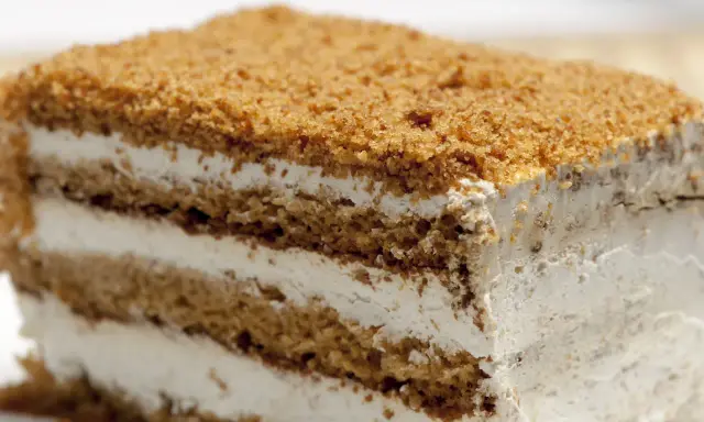Tranche de gâteau aux couches de biscuit et de crème, saupoudrée de miettes.