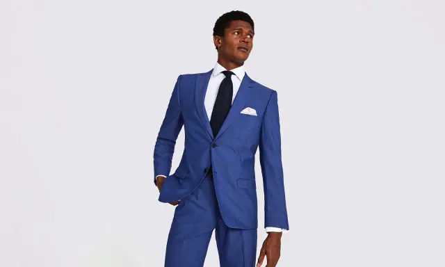 A man in a sharp blue suit, white shirt, and dark tie. This image helps answer how much should a suit cost.