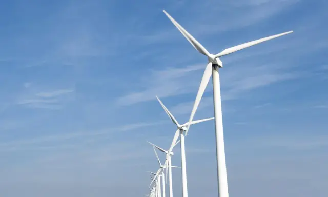 Reihe von Windrädern unter blauem Himmel, ein Symbol für Frankreichs Engagement für erneuerbare Energien.