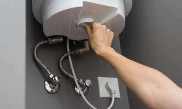 Mano girando el dial para cerrar la llave de paso del termo eléctrico.