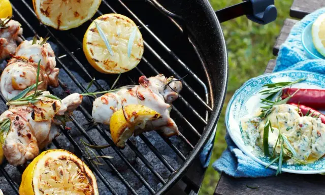 Grillad kyckling med citron och rosmarin på grillen, redo att serveras med en krämig röra och chili.