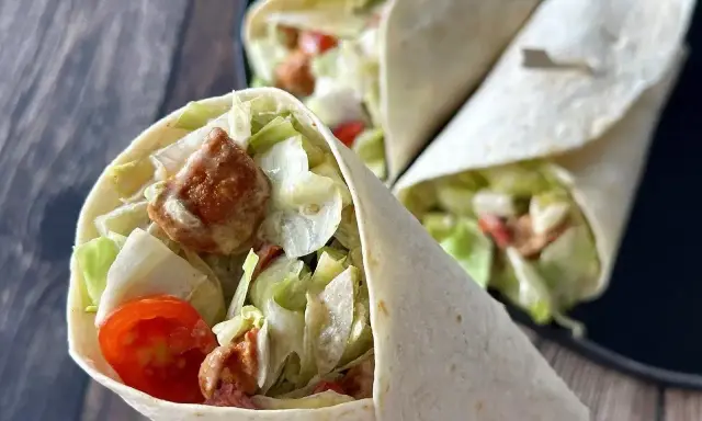 Pyszna tortilla z kurczakiem, chrupiącą sałatą i pomidorkami. Idealna na szybki lunch.