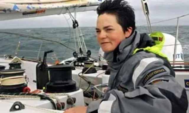 La navigatrice Ellen MacArthur, compagnon de bord sur un voilier, ajuste une voile.