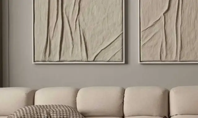 Deux tableaux texturés, style diy tableau relief, aux tons sable, accrochés au-dessus d'un canapé beige.