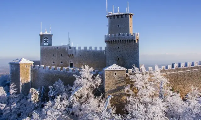 Le tre torri di San Marino innevate, un magico **percorso 3 torri San Marino** sotto un cielo azzurro.