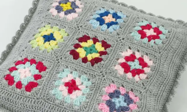 Szare szydełkowe poszewki na poduszki z kolorowymi wzorami w stylu granny square.