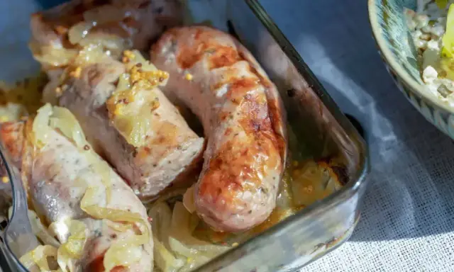 Aromatyczna, pieczona biała kiełbasa z cebulką i musztardą w szklanym naczyniu.