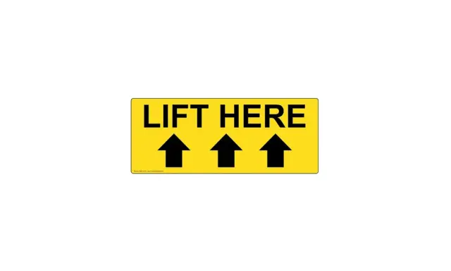 Żółty znak z napisem "LIFT HERE" i trzema czarnymi strzałkami skierowanymi w górę. To jasny znak tu chwytać, by podnieść przedmiot.