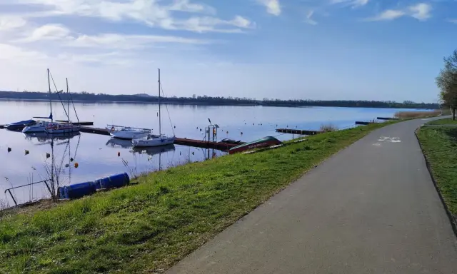 Jezioro Pogoria 4 z łodziami przy pomoście i ścieżką rowerową.
