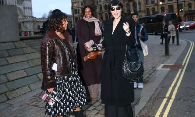 Un elegante cappotto a vestaglia nero, indossato con disinvoltura, si abbina perfettamente a un look audace e moderno.