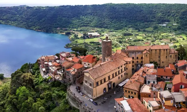 Nemi, un borgo incantevole a breve distanza da Roma, si affaccia sul lago. Case con tetti rossi si aggrappano alla collina, circondate da verde lussureggiante.