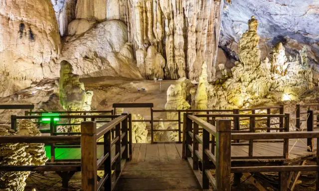 Drewniana kładka prowadzi przez imponujące jaskinie w Polsce, ukazując stalaktyty i stalagmity.