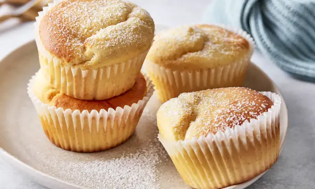 Saftige Quark Muffins, mit Puderzucker bestäubt, auf einem Teller arrangiert. Ein köstlicher Genuss!