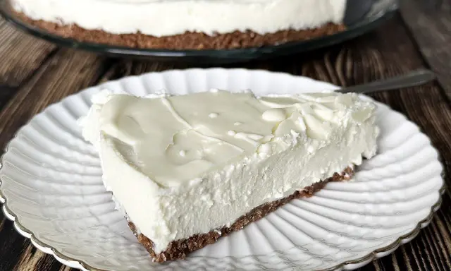 Pyszny sernik na zimno z kremową masą i chrupiącym spodem, podany na białym talerzyku.