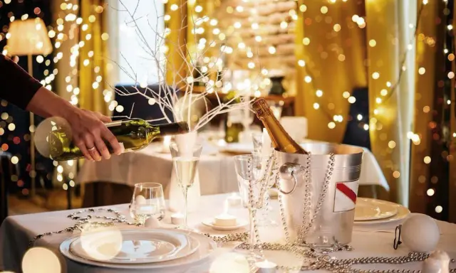 Mesa festiva con luces navideñas, champán y vino. Ideas para decorar un bar para Navidad con estilo y elegancia.