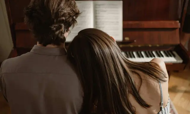 Pareja compartiendo un momento íntimo junto a un piano, el verdadero **exclusividad significado** de la conexión.