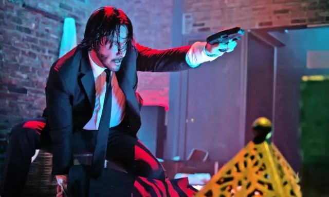 John Wick i svart kostym, med pistol i hand, redo för strid. Kanske en scen från John Wick 5.